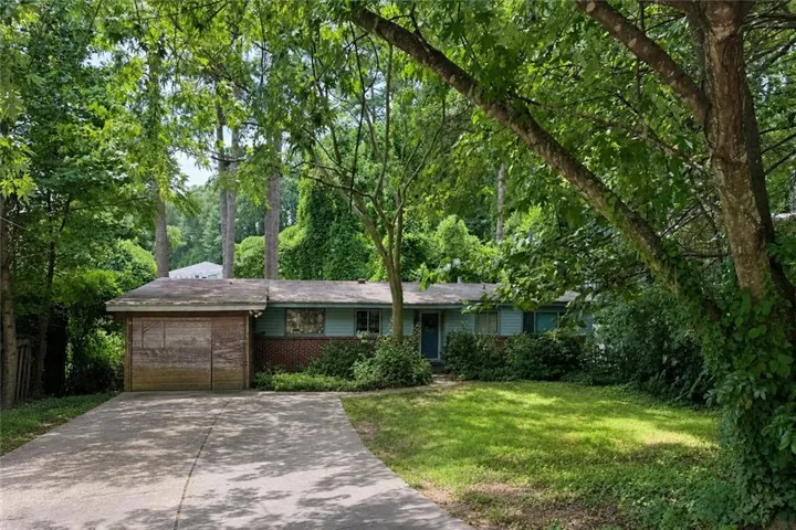Ranch-style residence featuring a brick and siding exterior, a wood-paneled garage door, and a concrete driveway