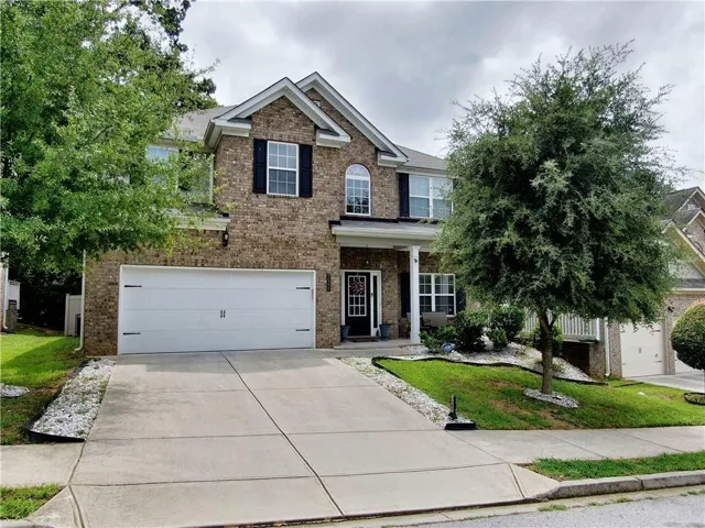 Traditional-style residence featuring a brick facade, white two-car garage, and a concrete driveway