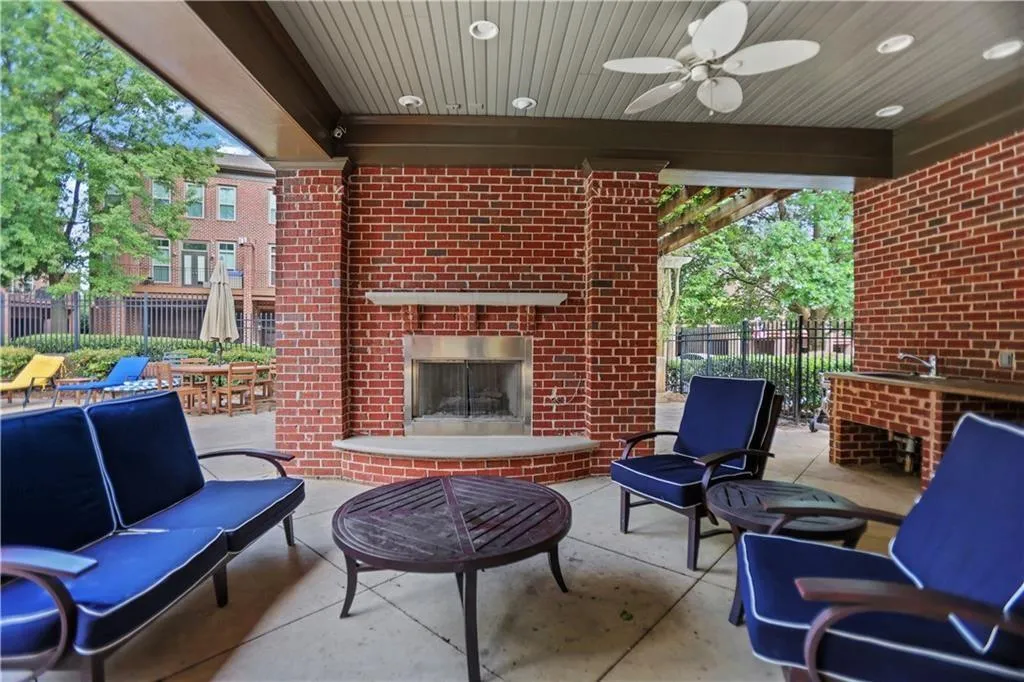 View of patio with fence, a ceiling fan, an outdoor living space with a fireplace, and a sink