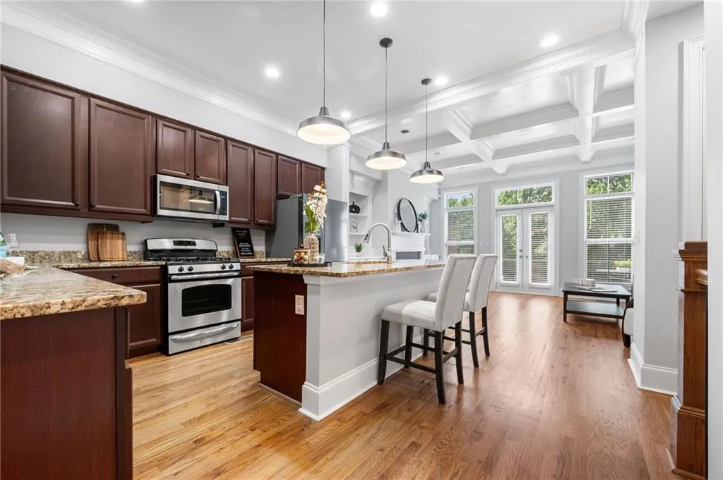 Kitchen featuring stainless steel appliances, recessed lighting, ornamental molding, a kitchen bar, and beam ceiling