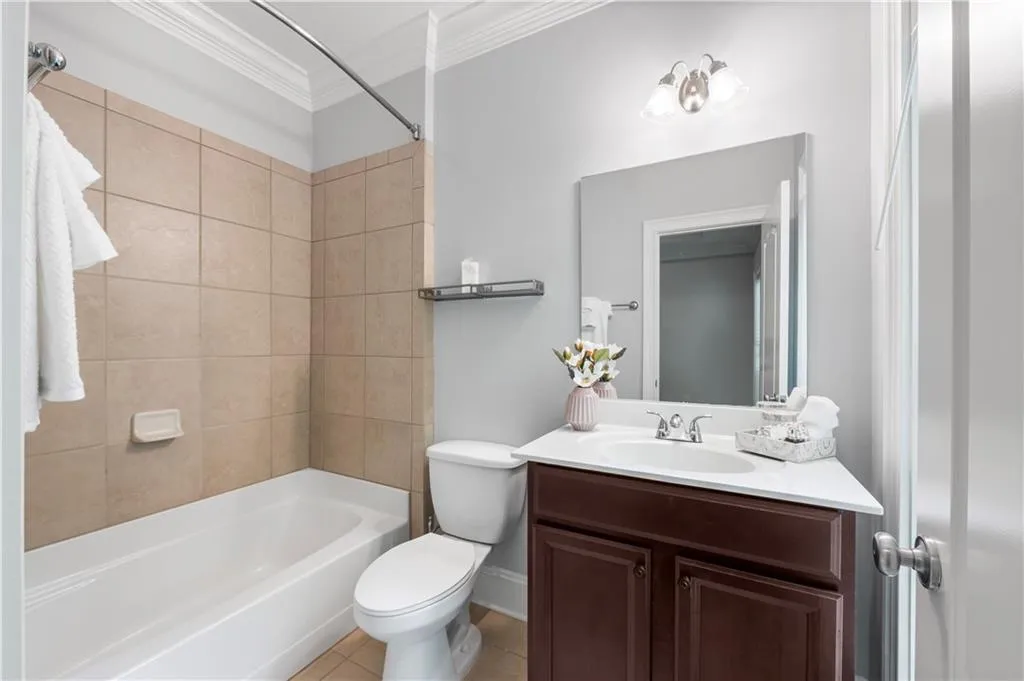 Bathroom with crown molding, toilet,  shower combination, vanity, and tile patterned flooring