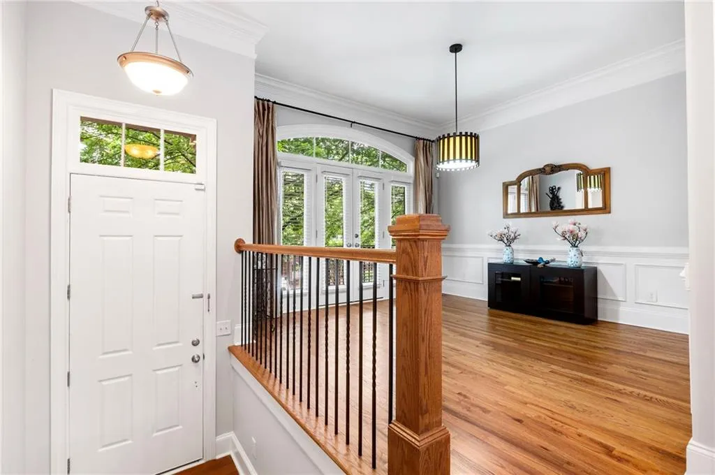 Entryway with healthy amount of natural light, light wood-style floors, crown molding, and wainscoting