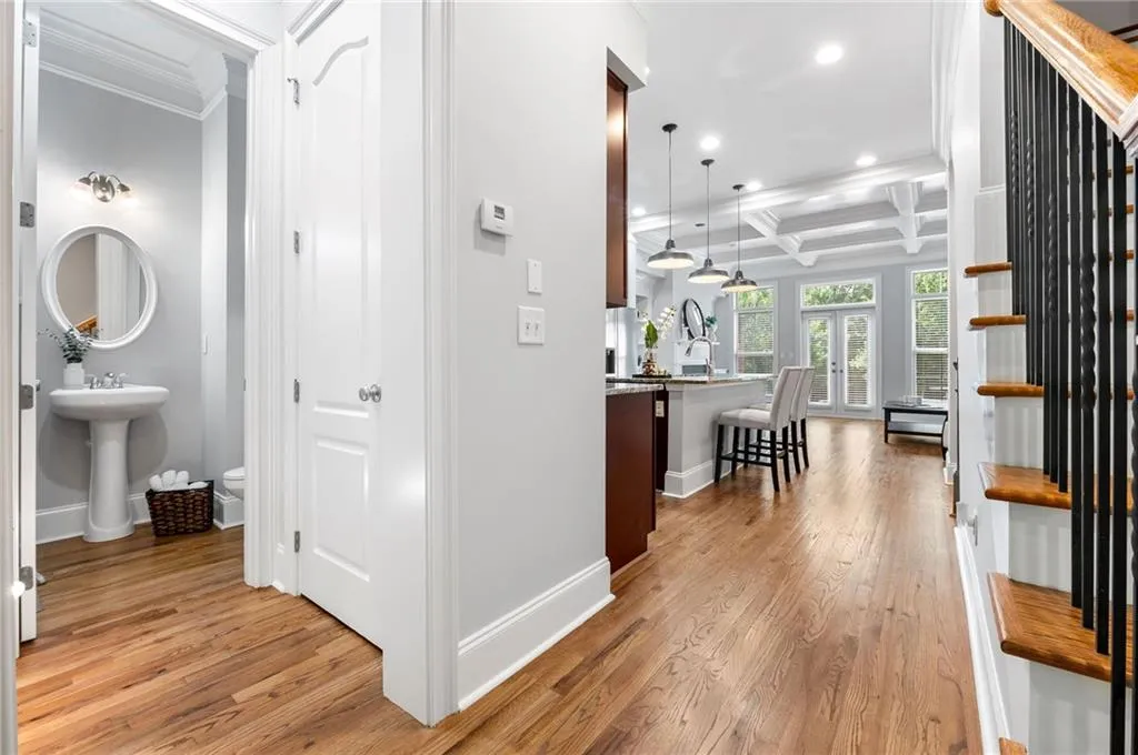 Corridor with crown molding, coffered ceiling, recessed lighting, light wood-style flooring, and baseboards