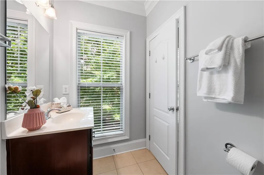 Bathroom with ornamental molding, tile patterned flooring, vanity, and baseboards
