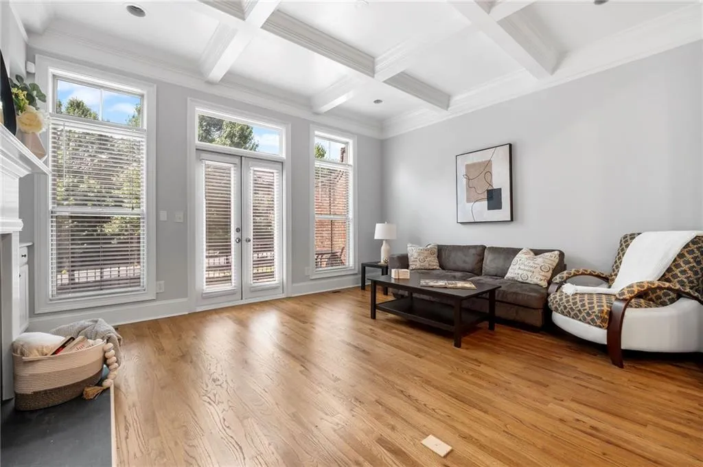 Living area featuring light wood-style flooring, beamed ceiling, coffered ceiling, french doors, and ornamental molding