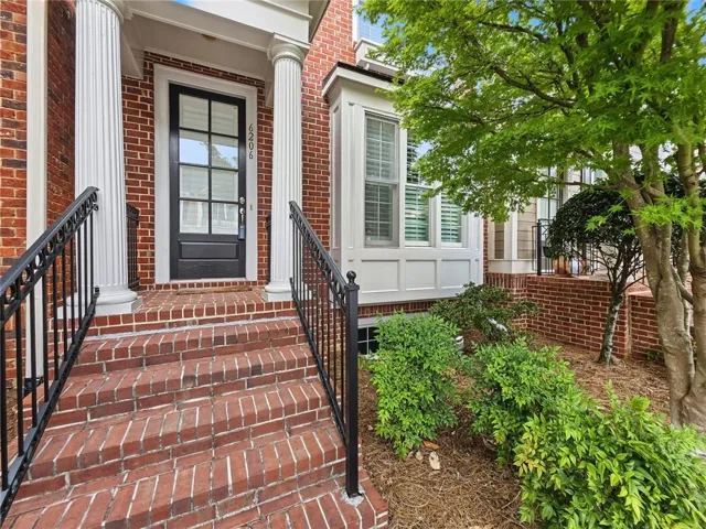 Brick exterior with a prominent bay window, a paneled entry door with glass inserts, and substantial fluted columns