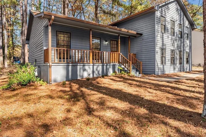 Light blue siding exterior featuring multiple windows and a covered porch with wooden railings and steps