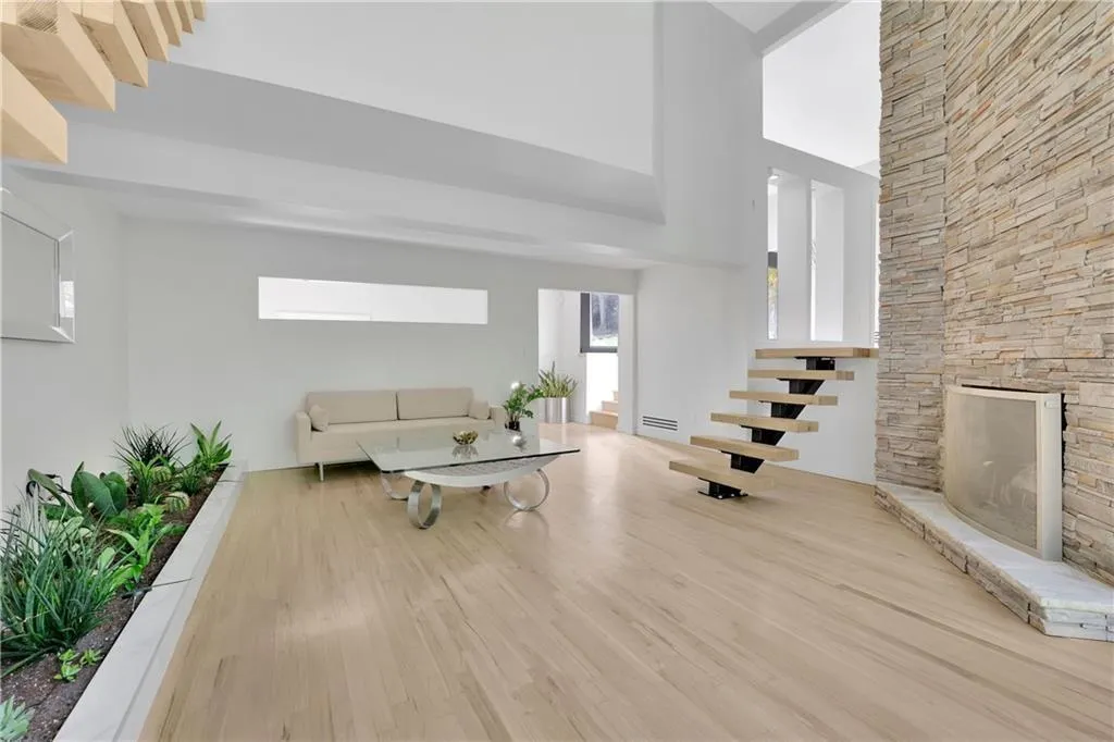 Living room featuring wood finished floors, a fireplace, a high ceiling, and stairs