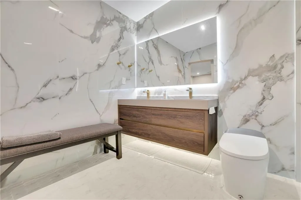 Bathroom with vanity, stone wall, and marble tiled flooring