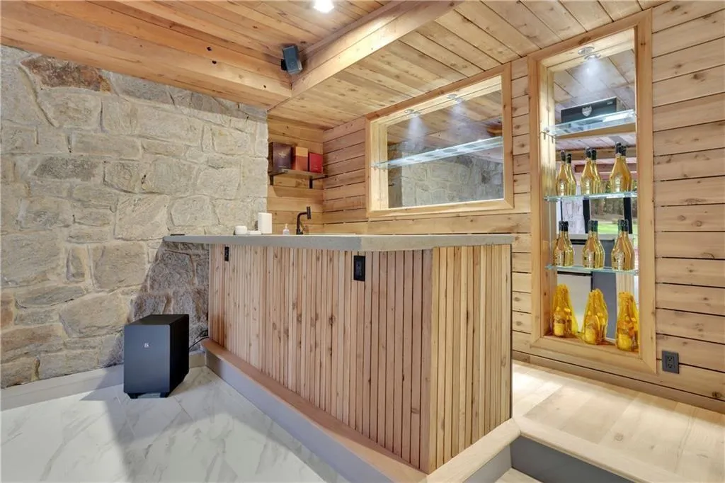 Indoor wet bar featuring wooden ceiling, light marble finish floors, and wooden walls