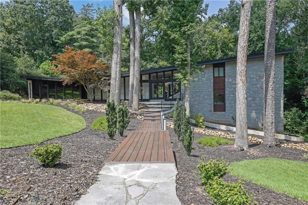 View of front of house with stone siding, a front yard, and a patio area