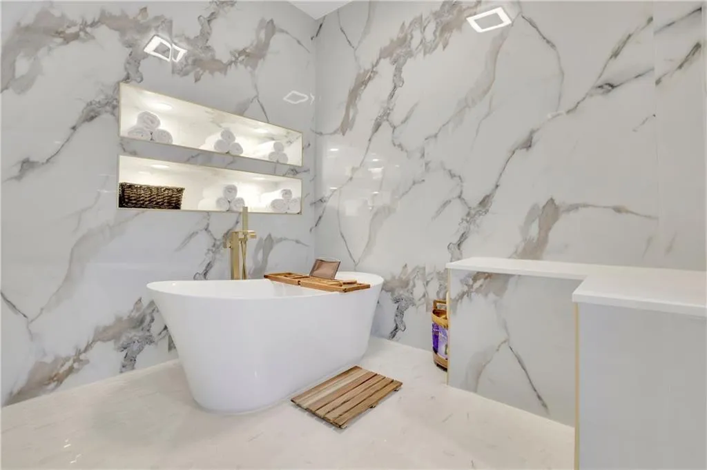Full bath featuring a freestanding tub and stone wall