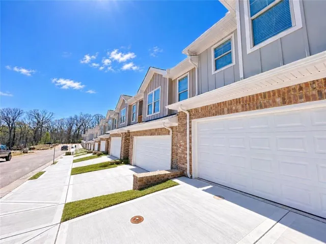 Brick and siding exterior, concrete driveway, attached garage, well-defined sidewalk, and manicured lawn strips