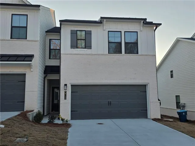 Painted brick facade, board and batten siding, black window frames, dark gray garage door, and a covered entry