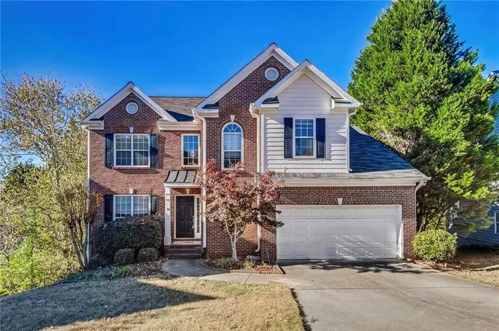 Brick exterior with white siding accents, an attached two-car garage, and a covered entryway