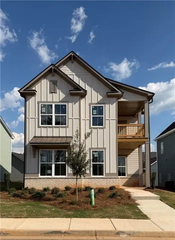 Two-story residence featuring vertical siding, a covered balcony, and a brick foundation