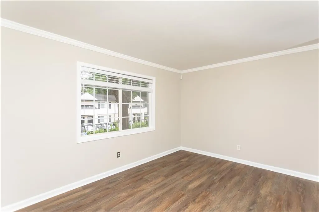 Spare room with ornamental molding and dark wood-style flooring