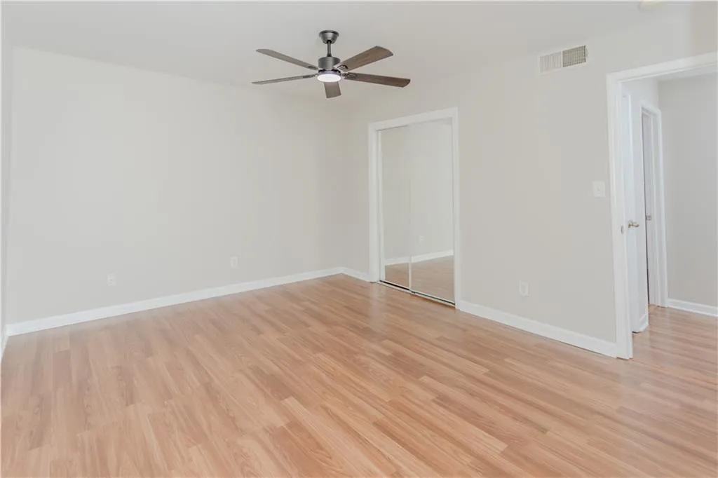 Empty room with ceiling fan and light wood-style flooring