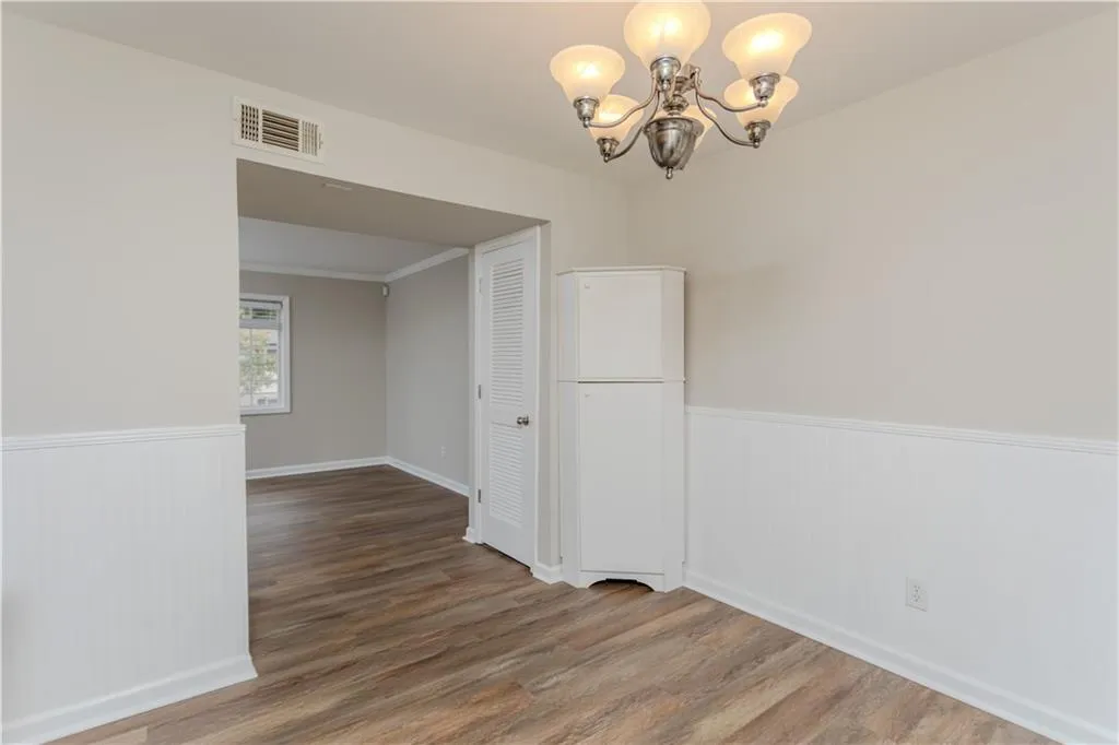 Unfurnished room with a wainscoted wall, wood finished floors, and a chandelier