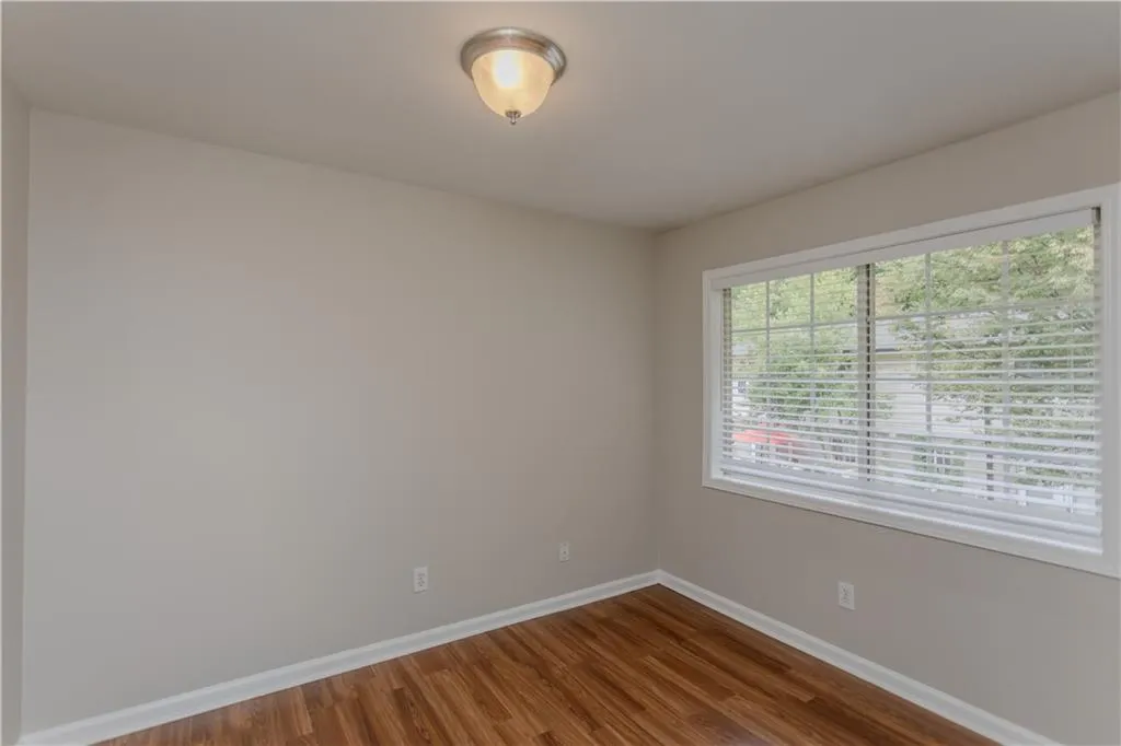 Spare room featuring baseboards and dark wood-type flooring