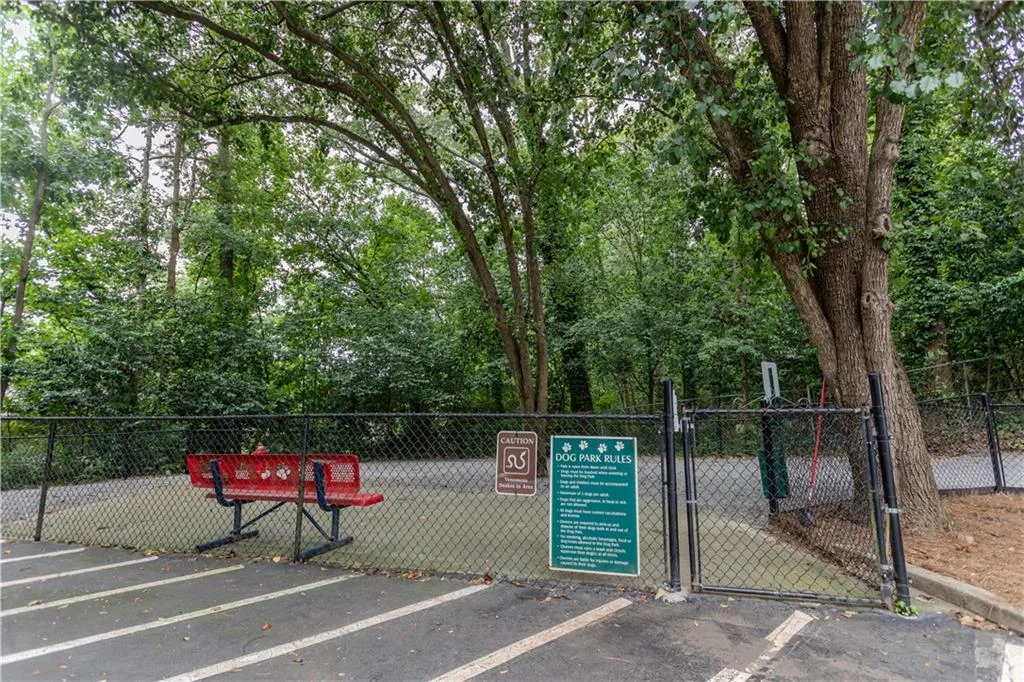 View of home's community with a gate, uncovered parking, and view of scattered trees