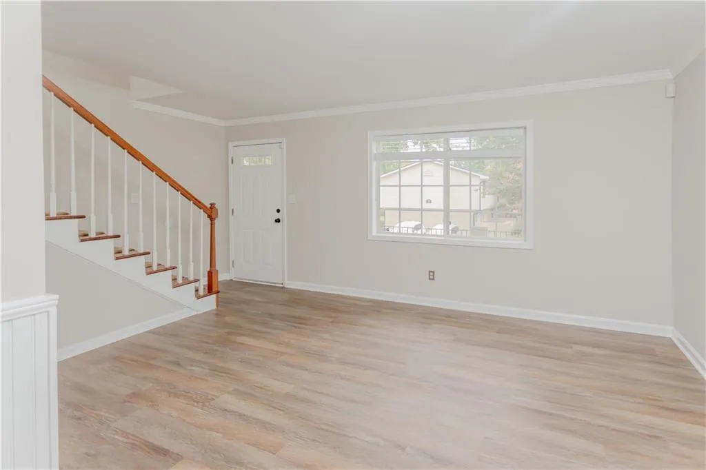 Entrance foyer featuring crown molding, light wood-style flooring, and stairway
