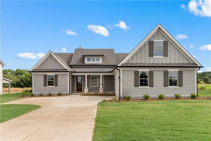 Contemporary farmhouse exterior with light gray siding, dark gray shutters, a covered entry porch, and a dormer window