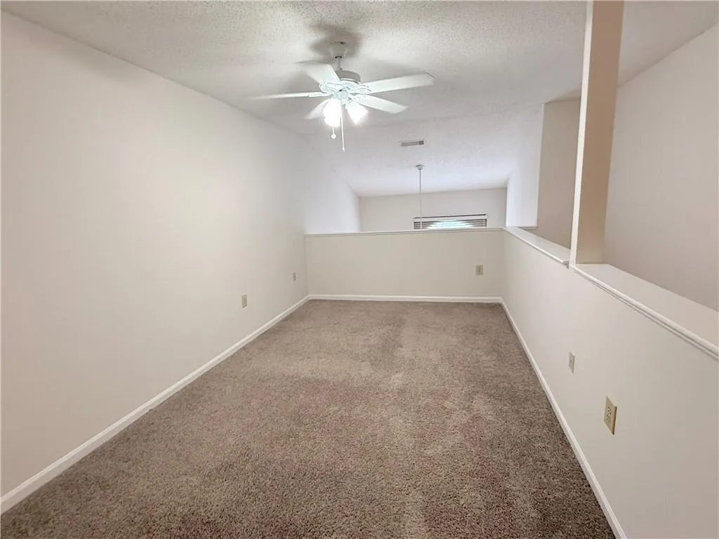 Unfurnished room featuring a ceiling fan, a textured ceiling, and carpet floors