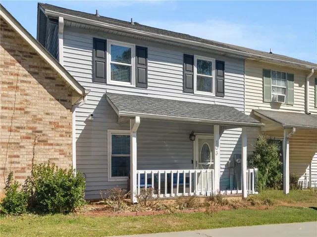 Traditional-style home featuring a shingled roof, covered porch, and a front lawn