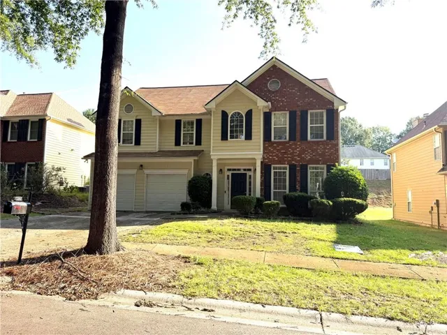 Two-story residence featuring a brick facade with siding accents, arched transom window, and a two-car garage