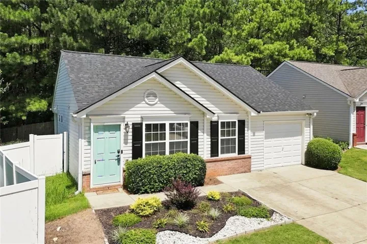 White vinyl siding residence featuring a teal front door, dark shingle roof, and an attached single-car garage