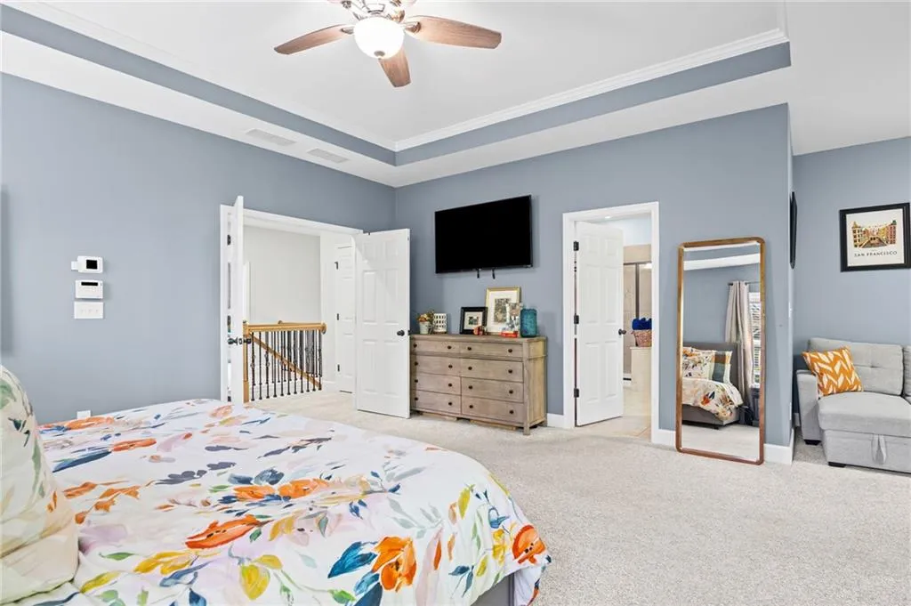 Primary bedroom with crown molding, a ceiling fan, and a raised ceiling