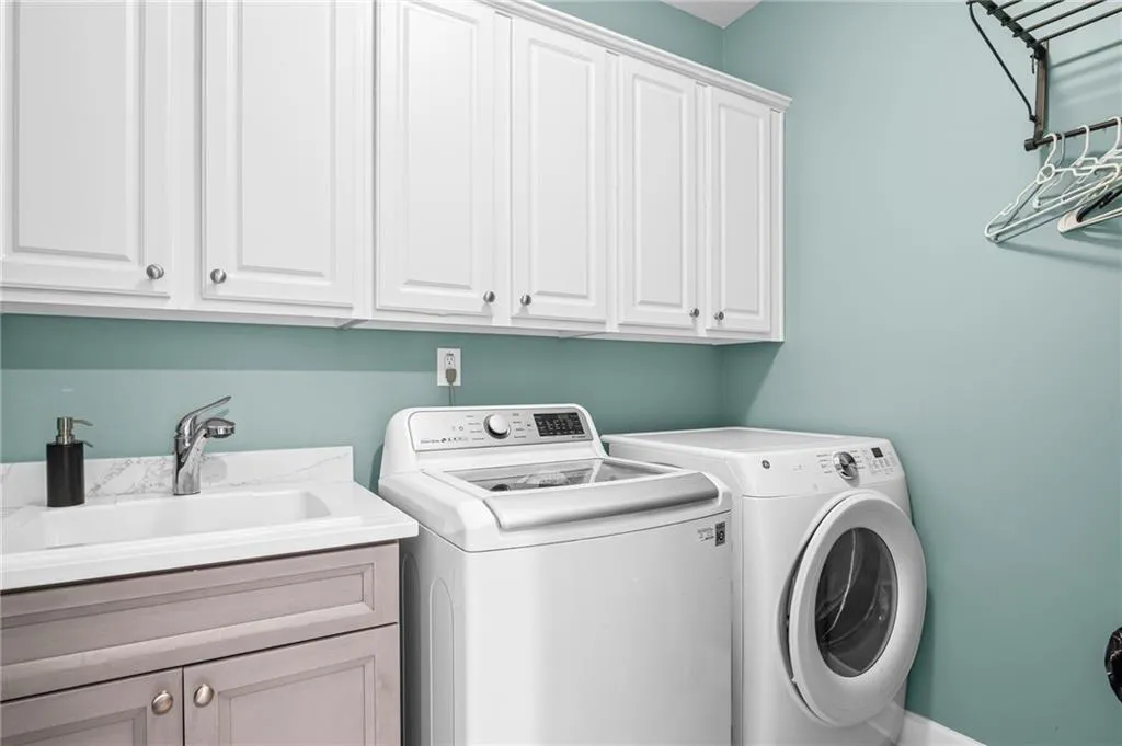 Laundry area featuring washing machine and clothes dryer with cabinet space and laundry sink