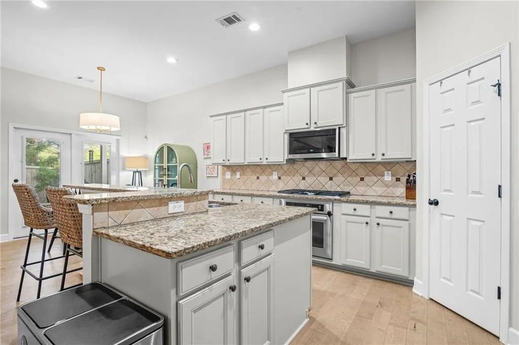 Kitchen featuring a kitchen bar, light wood-style flooring, light stone countertops, and gray cabinetry