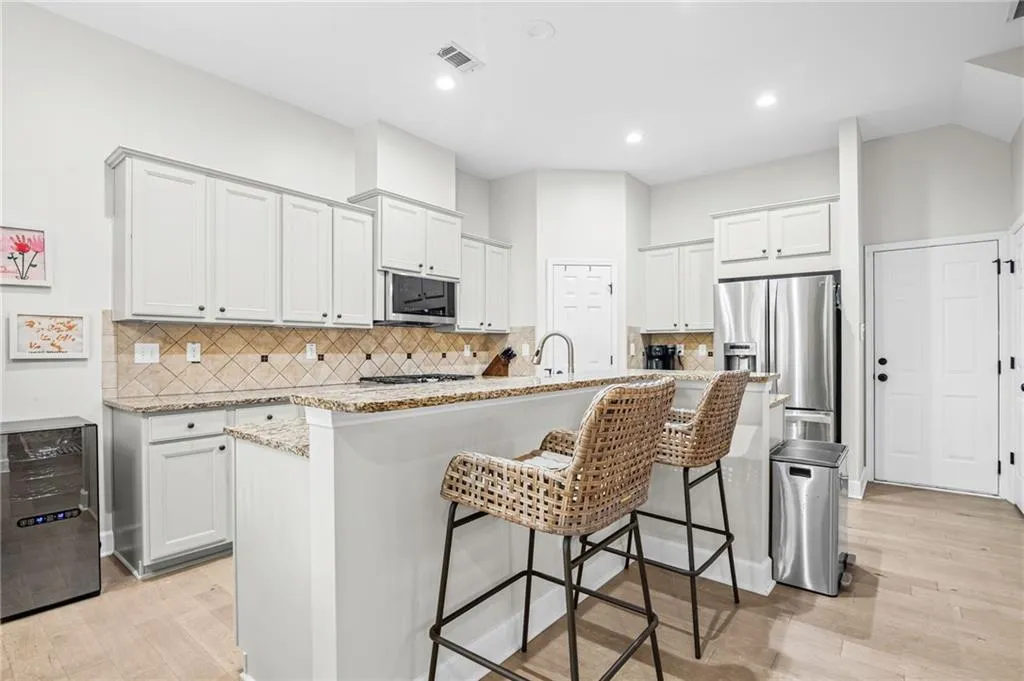 Kitchen with decorative backsplash, gray cabinets, a kitchen bar, and recessed lighting