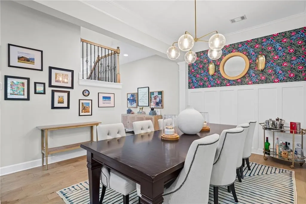 Dining area featuring a decorative wall, light wood-style flooring, a chandelier, wainscoting, and ornamental molding