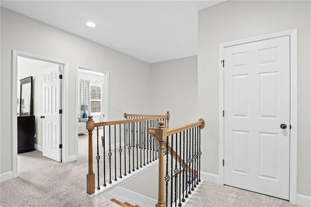 Hall with an upstairs landing and light colored carpet