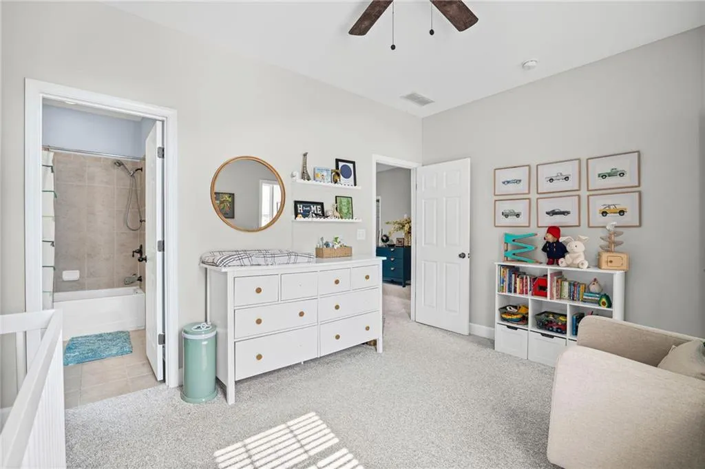 Bedroom featuring light carpet, ceiling fan, and ensuite bathroom