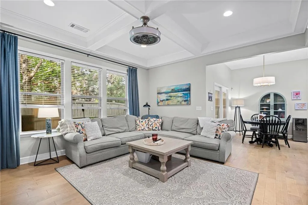 Living area with coffered ceiling, light wood-style flooring, and recessed lighting