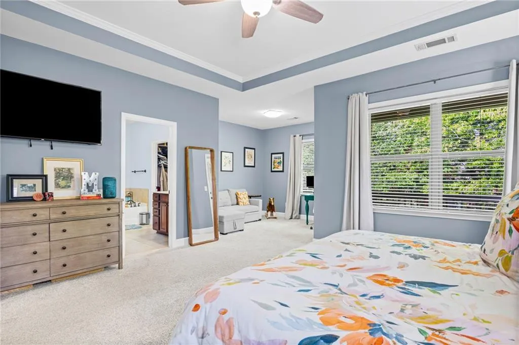 Primary Bedroom with crown molding, light carpet, ceiling fan, and ensuite bathroom