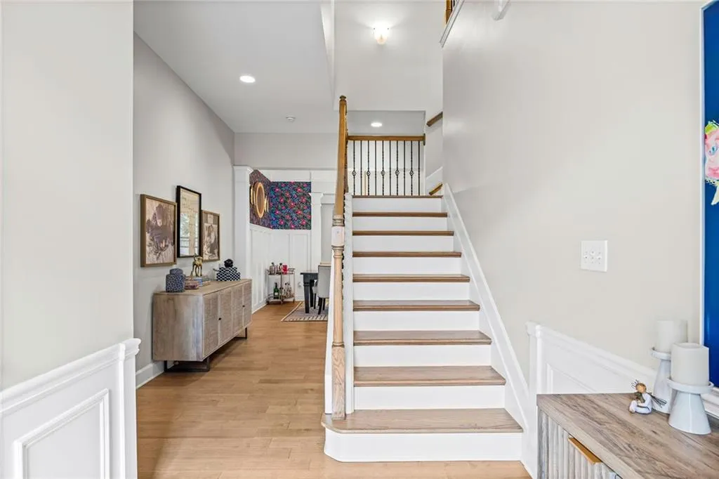 Staircase with a decorative wall, wainscoting, wood finished floors, and recessed lighting