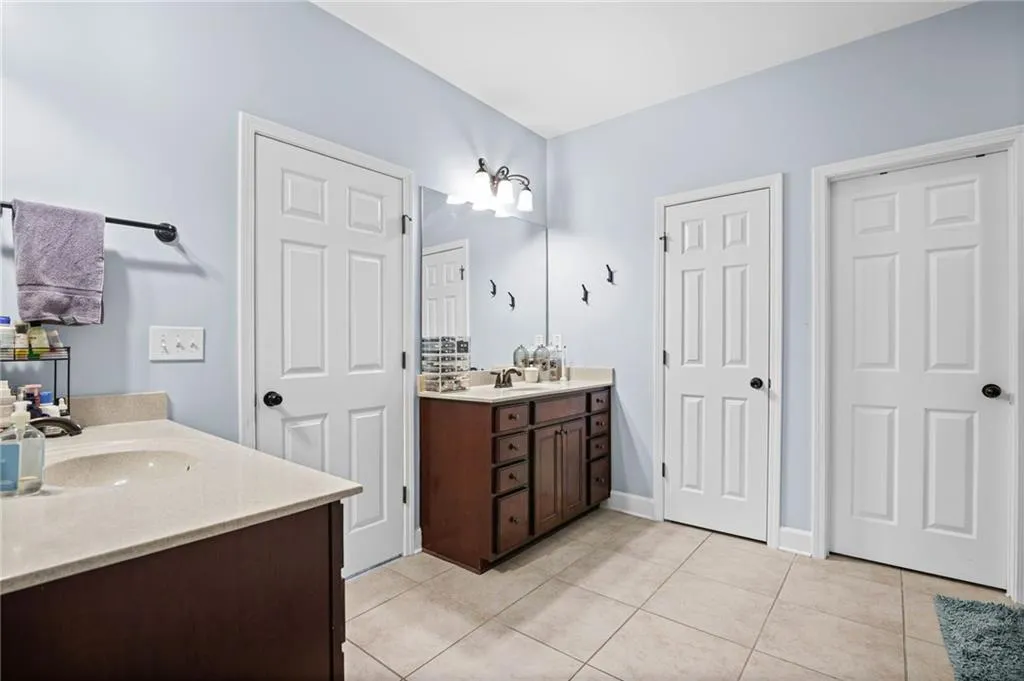 Primary Bathroom featuring two vanities and light tile patterned flooring
