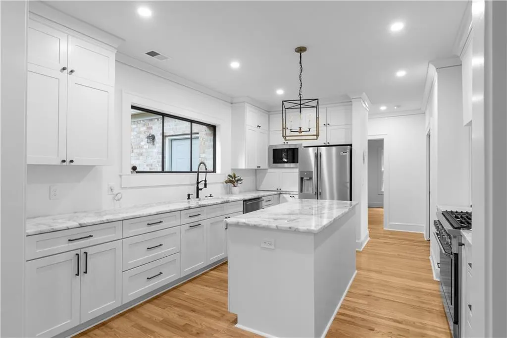 Kitchen with stainless steel appliances, a sink, ornamental molding, a center island, and white cabinets