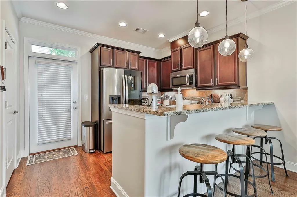 Kitchen featuring stainless steel appliances, a kitchen breakfast bar, a peninsula, ornamental molding, and light stone countertops
