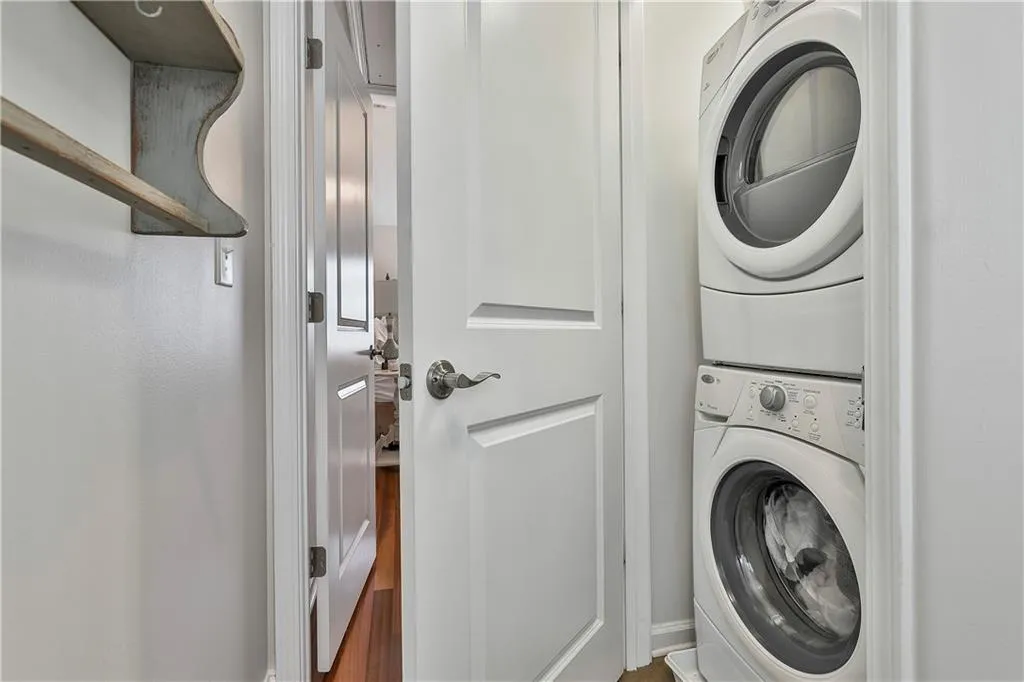 Washroom with estacked washer and dryer and wood finished floors