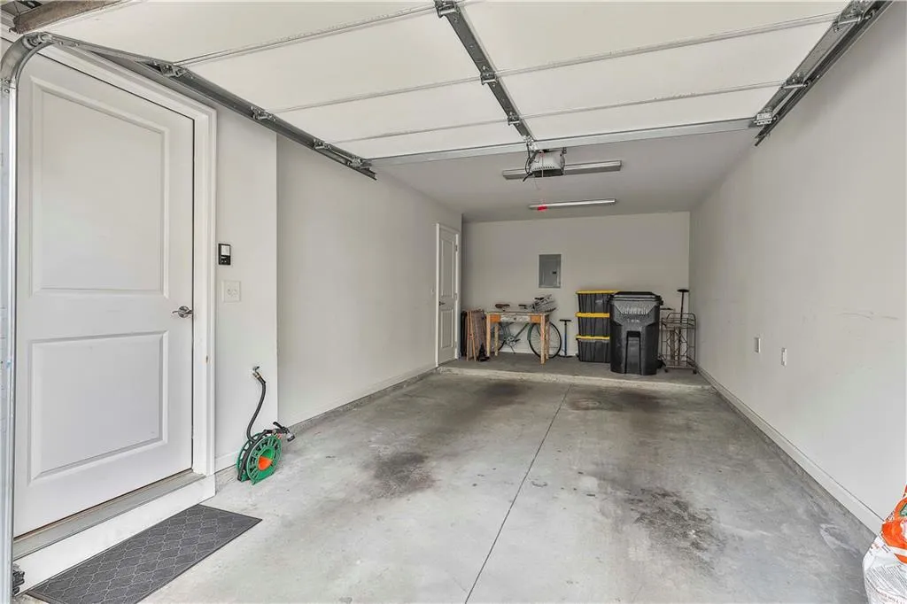 Garage featuring electric panel and baseboards