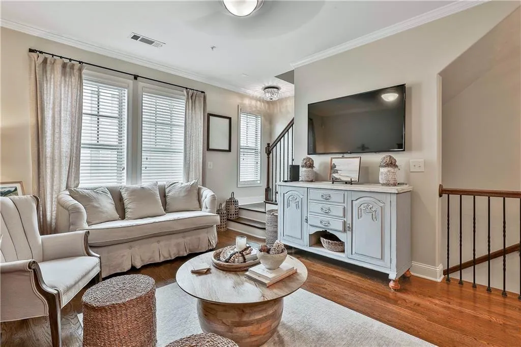 Living room featuring crown molding, healthy amount of natural light, stairs, wood finished floors, and ceiling fan