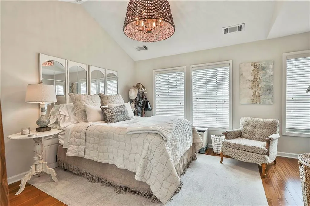 Bedroom featuring wood finished floors, a chandelier, and high vaulted ceiling