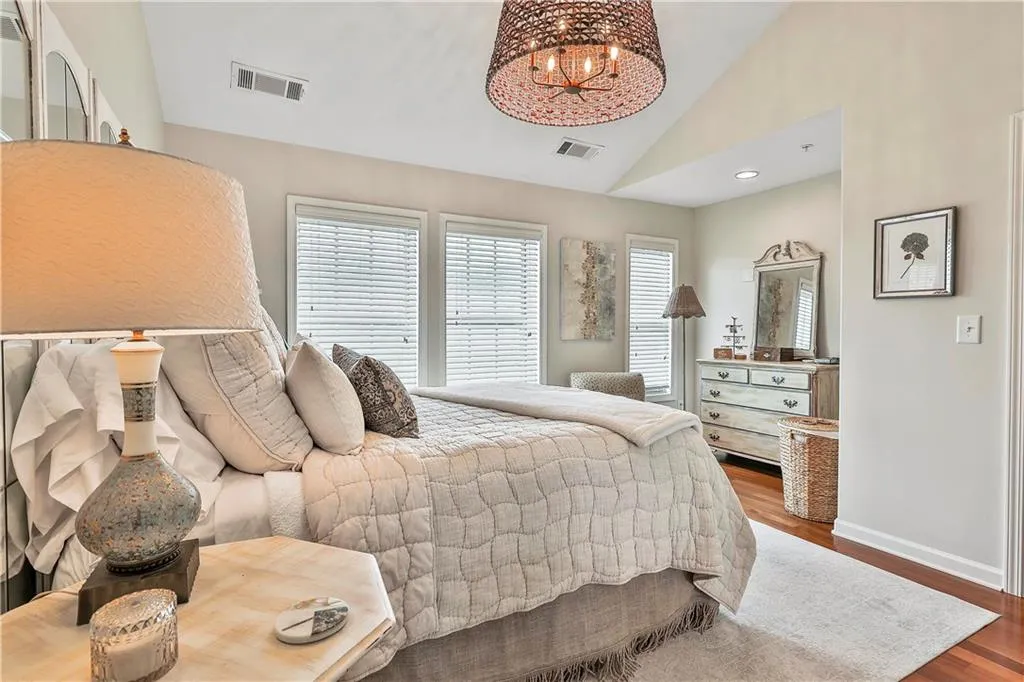Bedroom featuring wood finished floors, a chandelier, and high vaulted ceiling
