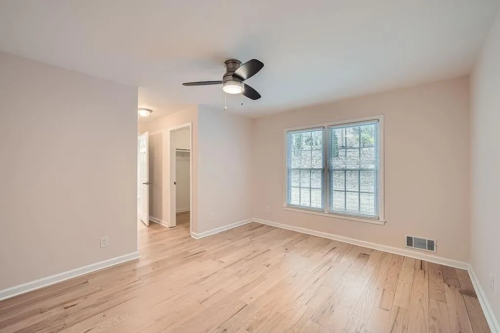 Unfurnished room with a ceiling fan, visible vents, light wood-style flooring, and baseboards